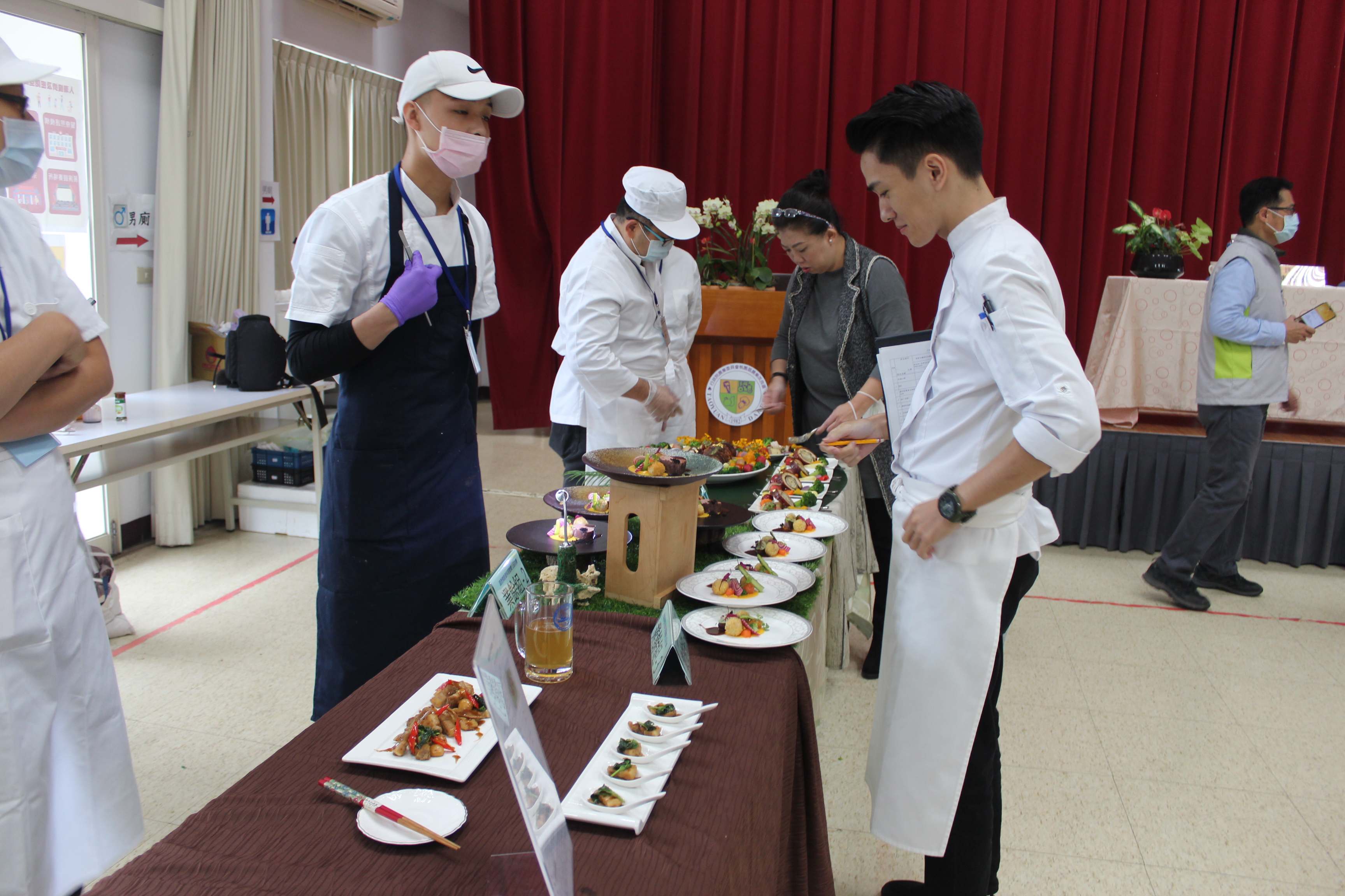 北區初賽時評審蔡季芳老師(右3)及陳佑昇老師(右2)正細細品嘗參賽料理。
