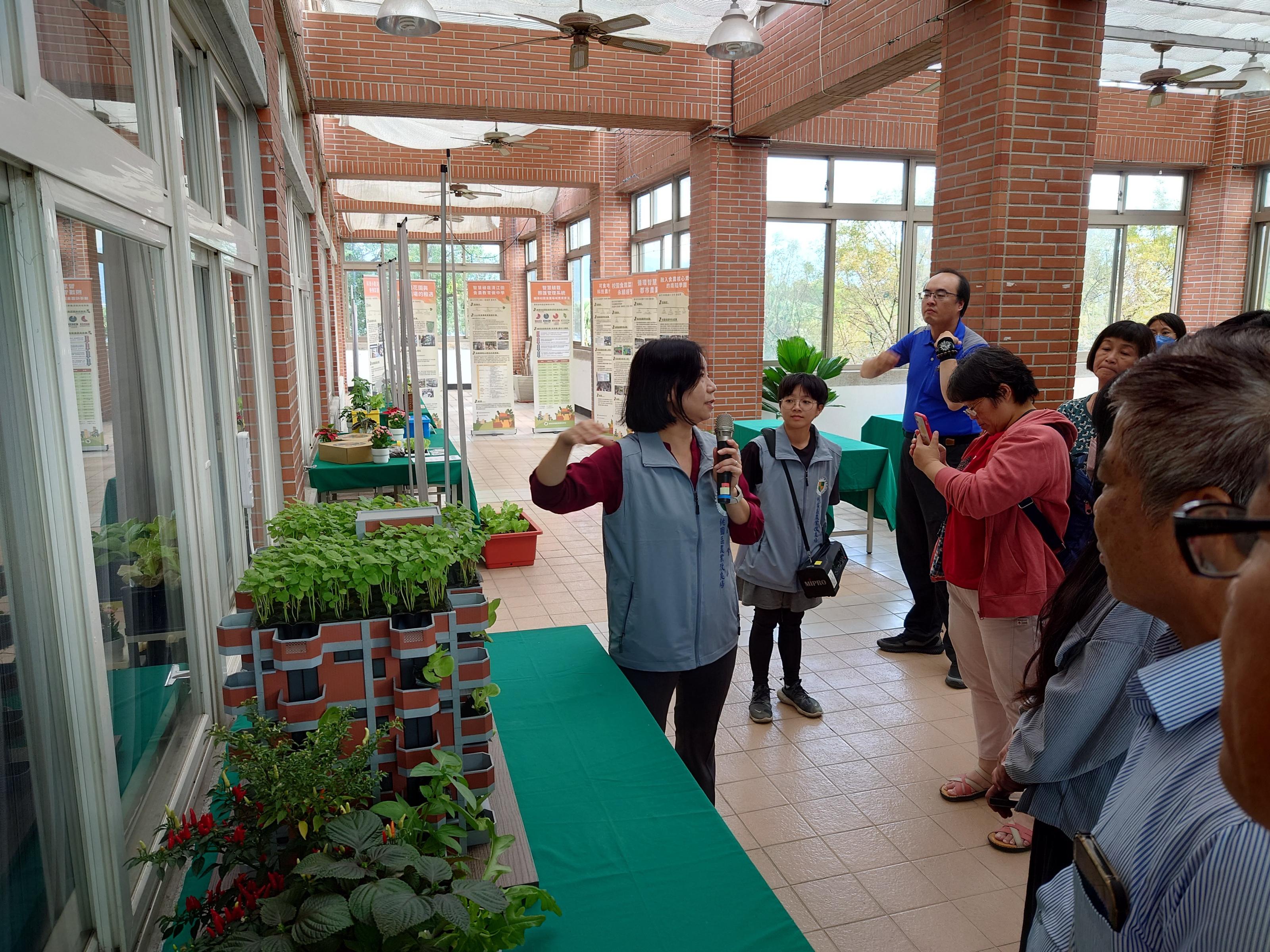 本場吳安娜副研究員(左一)於技術展示交流進行導覽，解說相關都市農業技術應用於食農教育場域之實況