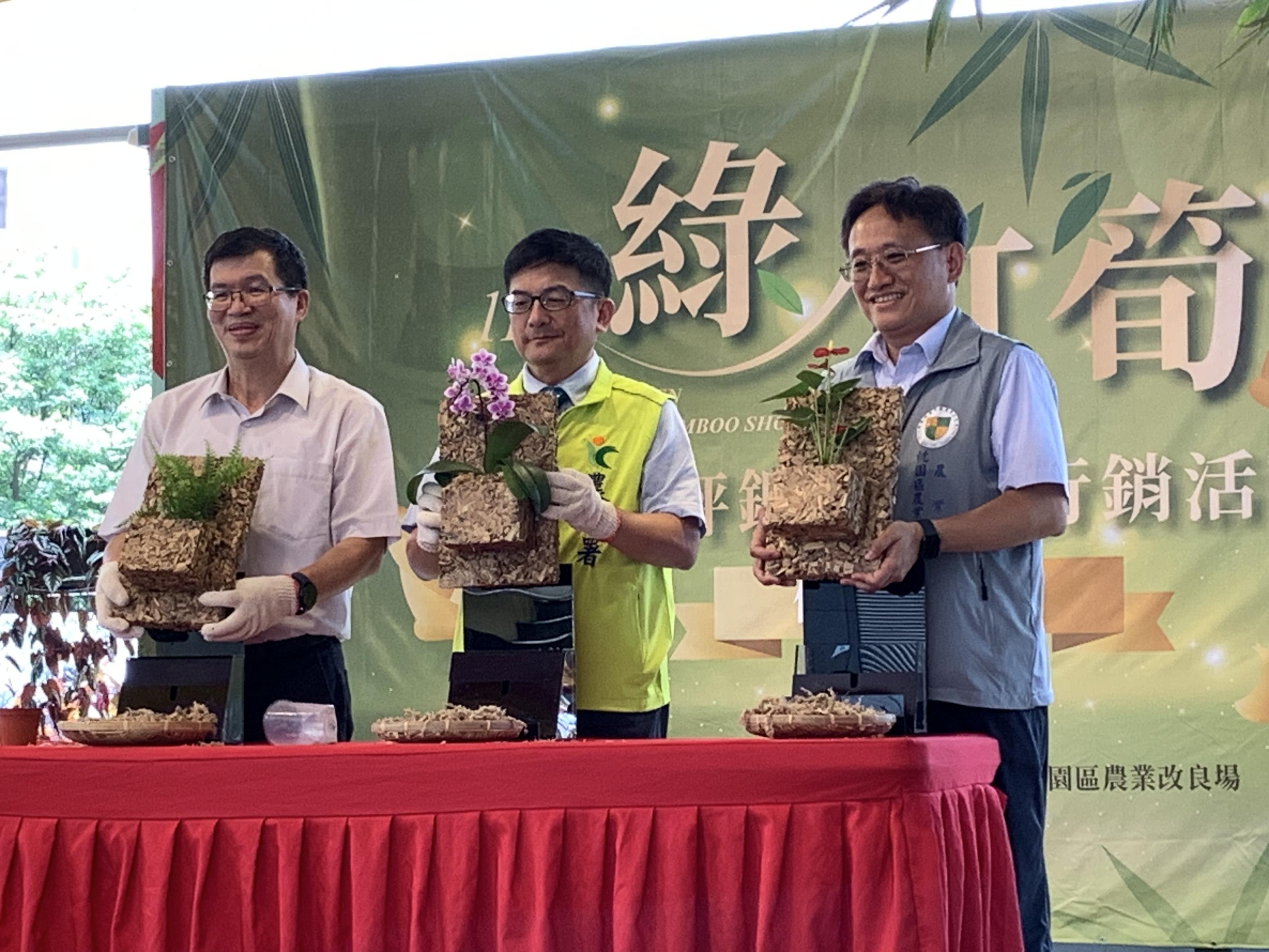 農糧署蘇茂祥代理署長(中)、北區分署黃昭興分署長(左)及本場郭坤峯場長(右)，於頒獎台上示範利用袋式綠竹板進行花卉植栽栽培