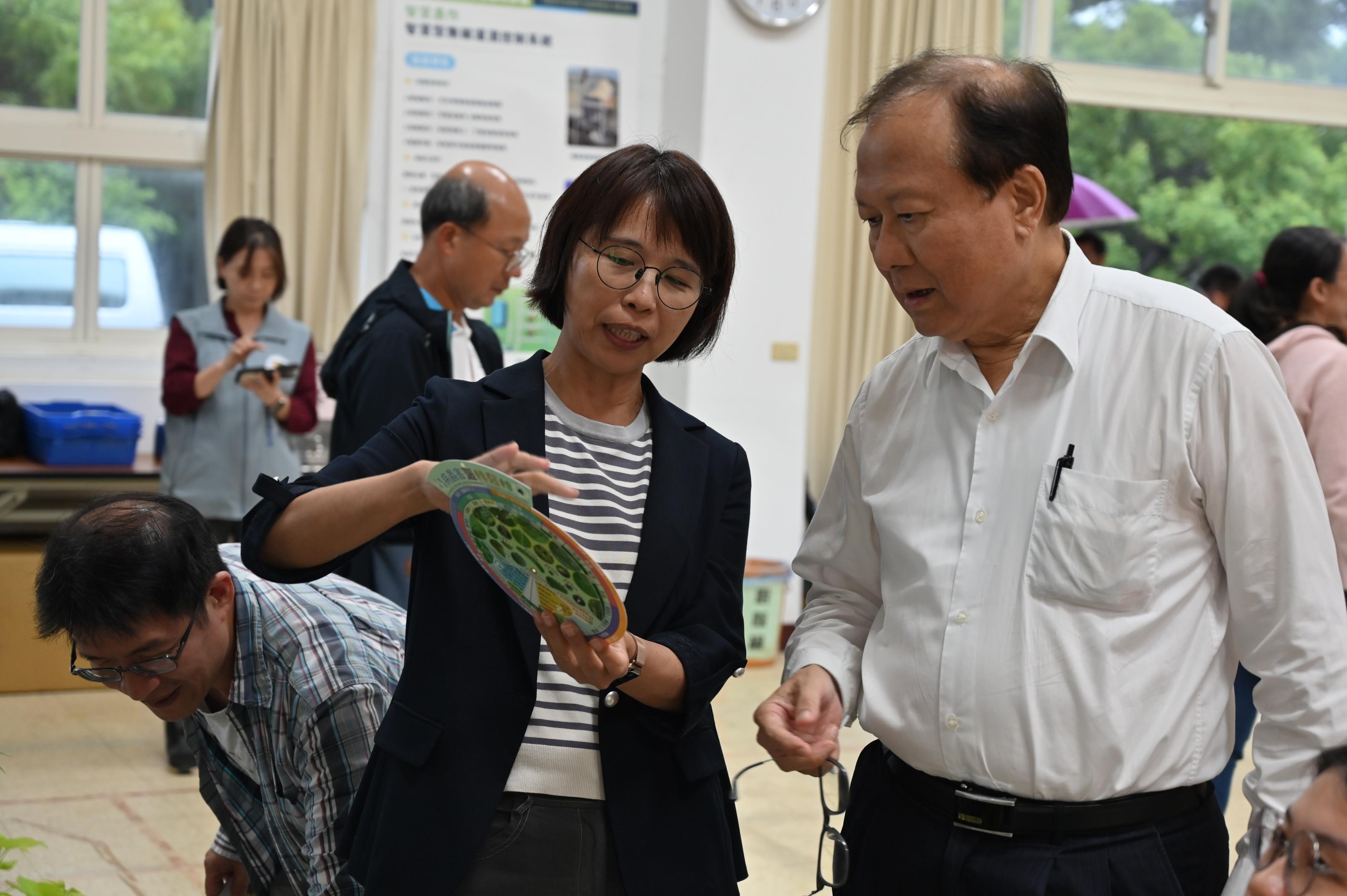 圖2.王毓華場長向蘇俊榮人事長解說病蟲害醫轉盤。
